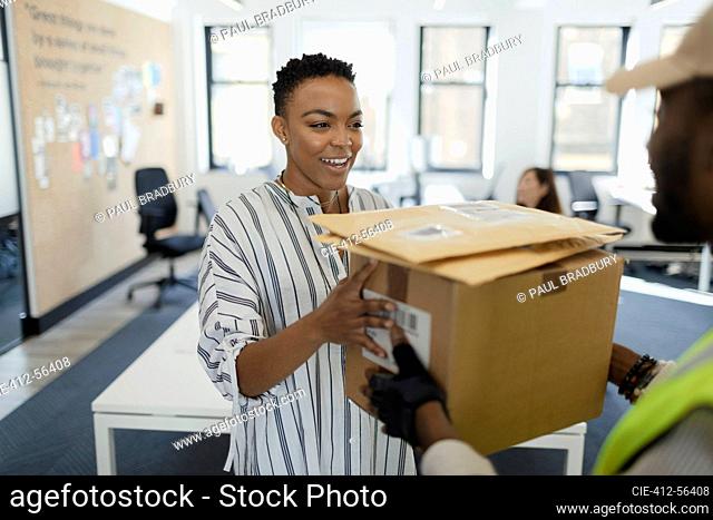 Happy businesswoman receiving packages from courier in office