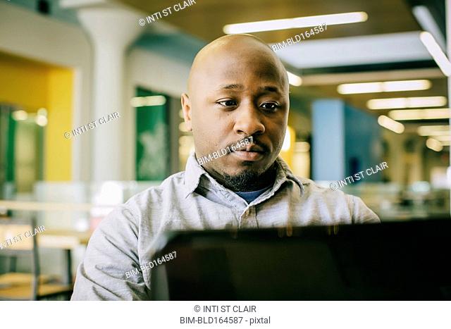 Black businessman using laptop in cafe