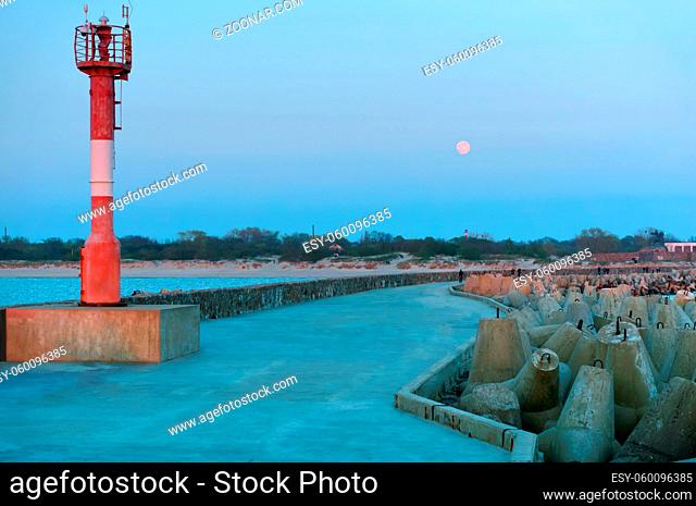 lighthouse on sea pier, promenade in the moonlight, pier with the coast fortifications