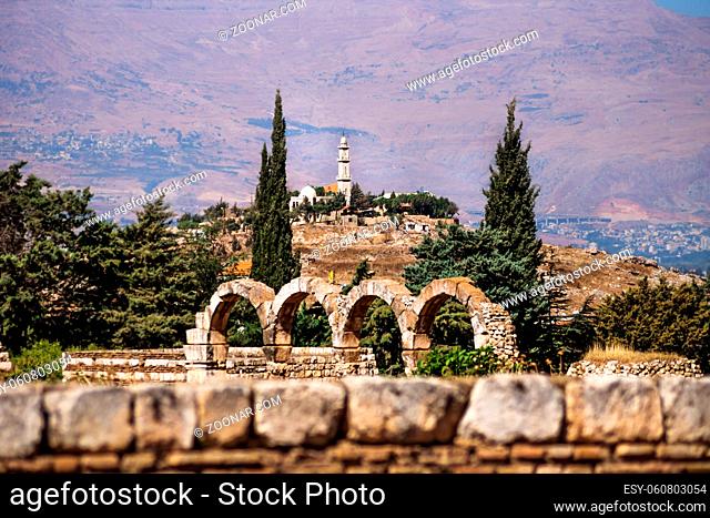 Mosque on a hill surrounded by pine trees with Mountains in the background on a sunny day at Anjar, Bekaa valley, Lebanon