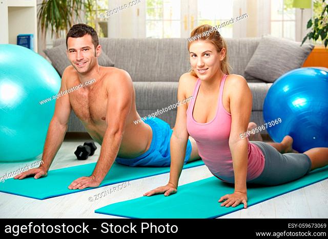 Young couple lying on fitness mattress and streching abdominal