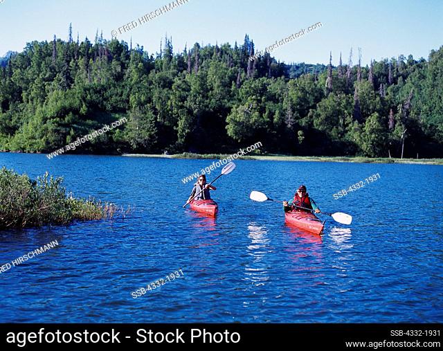 Jennifer Lambourne and John Phelps paddling kayaks on Beaver Lake of Big River Lakes, Redoubt Bay State Critical Habitat Area, Alaska