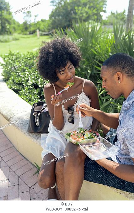 USA, Florida, Miami Beach, young couple sharing a salad in a park