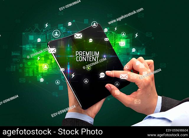 Businessman holding a foldable smartphone with PREMIUM CONTENT inscription, social networking concept