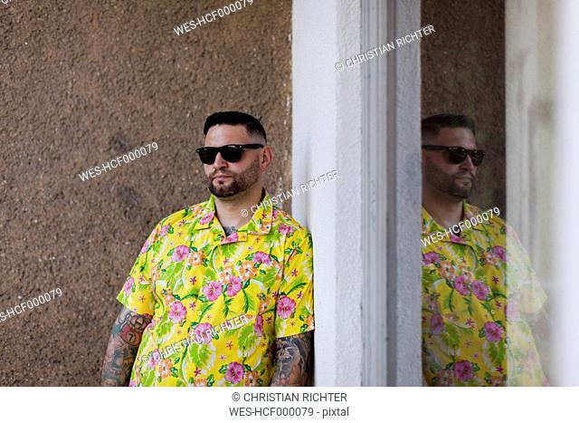 Man with fullbeard and tattoos wearing shirt with floral design and sunglasses