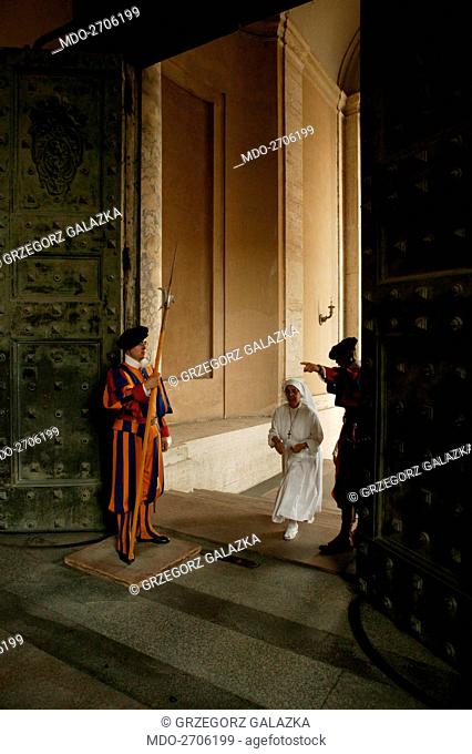 A Swiss Guard showing the road to a nun at the entrance of the Bronze Portal. Vatican City, 2000s