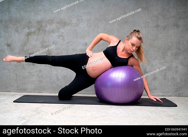 Portrait of pretty pregnant woman exercises with fitball in the gym. Working out and fitness, pregnancy concept