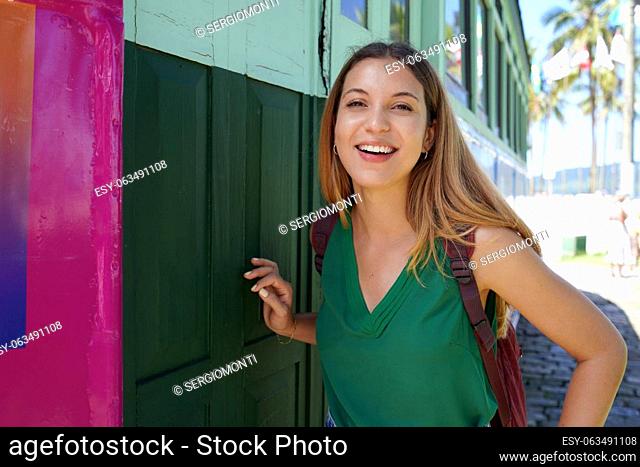 Portrait of smiling traveler girl with backpack posing looking at camera