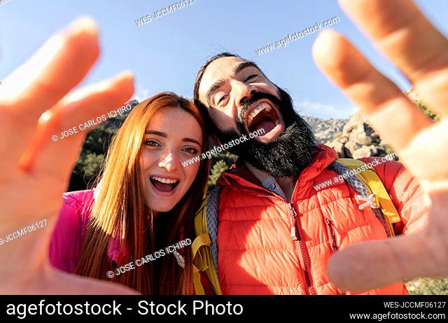 Happy couple with mouth open gesturing enjoying sunny day