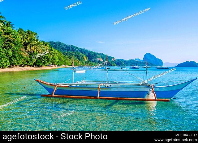 Traditional banca boat in clear water at sandy Corong Beach in El Nido, Philippines