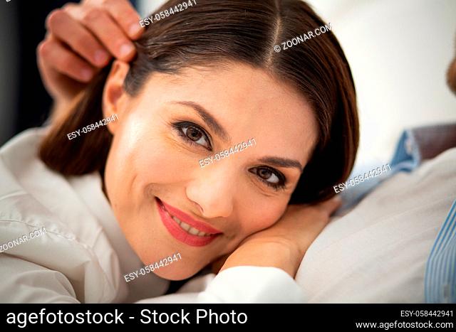 Happy lady laying on her boyfriends chest. Close up portrait of beautiful smiling woman resting on her husbands chest and looking at camera