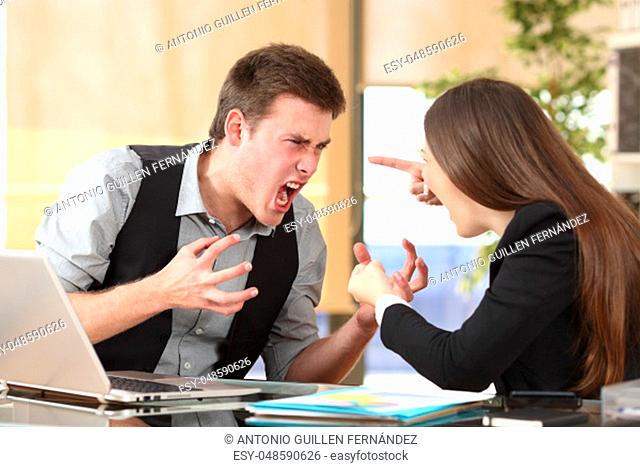 Two furious businesspeople arguing strongly in a desktop with an office background