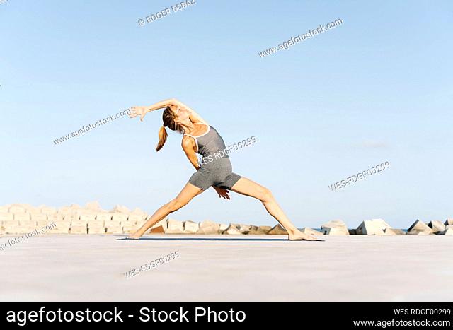 Mid adult sportswoman doing yoga on exercise mat