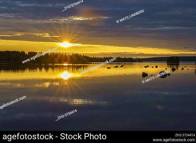 Sunset at Stora luleälven with nice color in the sky and reflection in the water, some rocks in the water, Jokkmokk, Stora luleälven, Swedish Lapland, Sweden