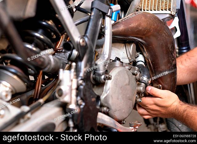 Motorbike mechanic repairing an exhaust pipe system at garage