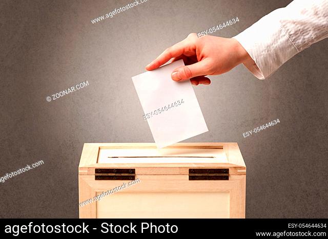 Ballot box with person casting vote on blank voting slip, grungy background