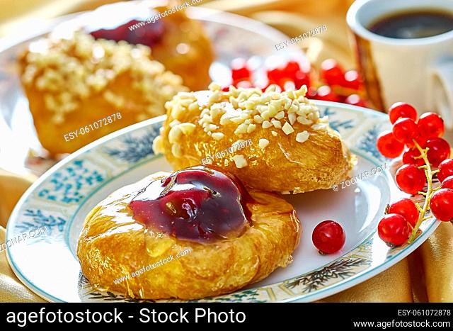cheesecake with jam on a plate against the background of the cup with a sprig of red currants Food being prepared and cooked in a contemporary kitchen