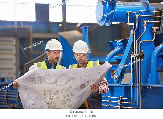 Engineers reviewing blueprints in factory