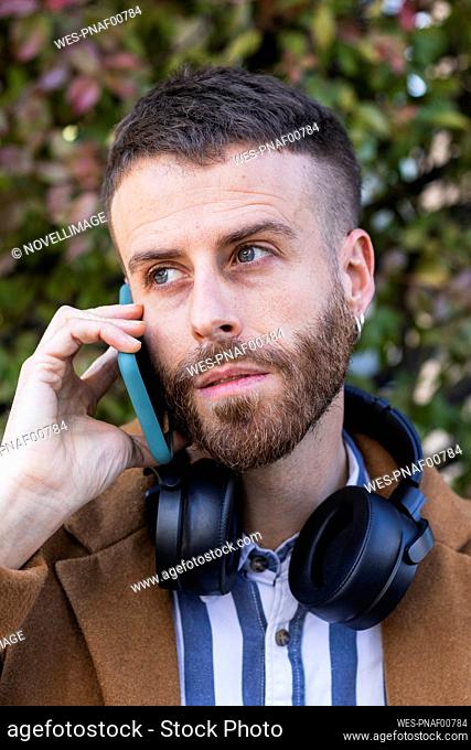 Businessman looking away while talking on mobile phone outdoors