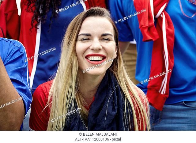 Woman watching football match, smiling cheerfully