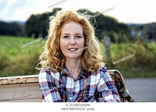 Portrait of woman sitting on pick up truck