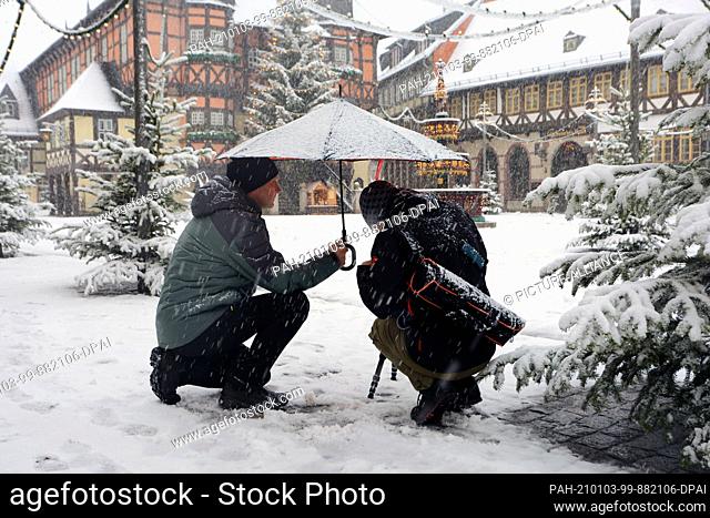 03 January 2021, Saxony-Anhalt, Wernigerode: Walkers take pictures of the city's marketplace. Snow fell across large parts of the country on Sunday