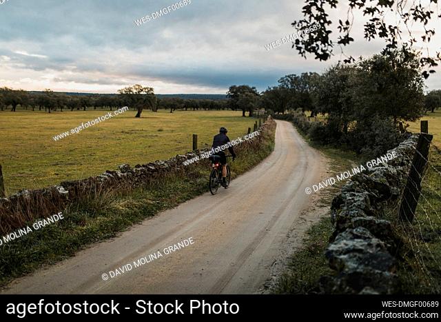 Cyclist riding bicycle on road at sunrise