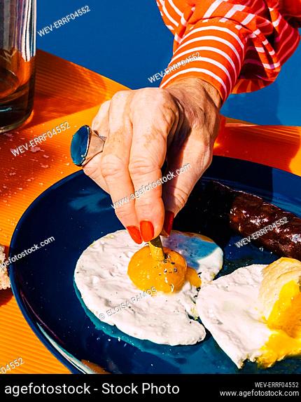 Hand of senior woman extinguishing cigarette in fried egg