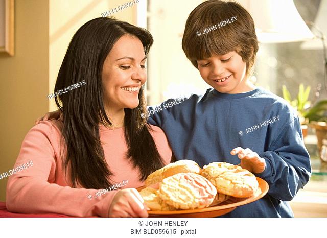 Hispanic mother and son holding plate of cookies