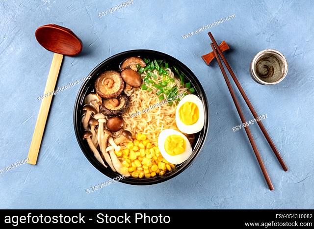 Ramen. Soba with eggs, mushrooms, and vegetables, shot from the top with sake, traditional wooden spoon, and chopsticks