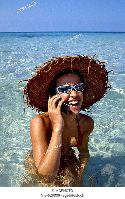 Spanien, Ibiza, junge Frau mit Sonnenbrille, Sonnenhut und Handy im Meer - Ibiza, Balearen,  Spanien, 27/07/2004