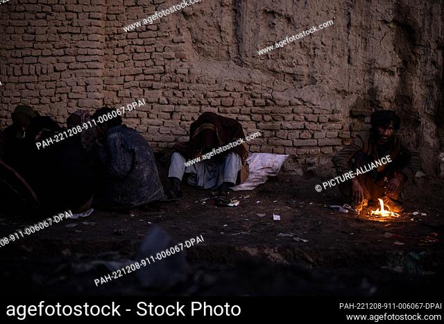 14 November 2022, Afghanistan, Kabul: Afghan men consume drugs on a side street of a market as dusk sets in. Drug addiction has been a long standing problem in...