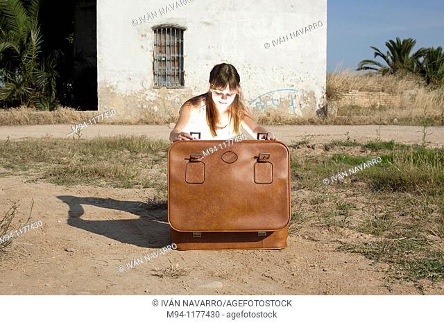 Woman opening an abandoned suitcase