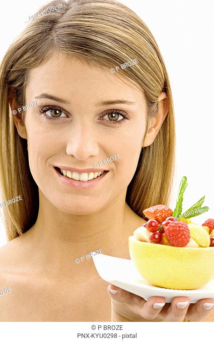Portrait of a young woman holding a bowl of fruit salad
