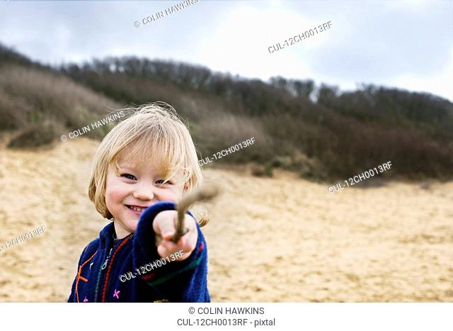 boy on beach pointing with stick