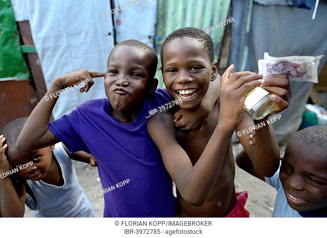 Two boys posing with money, alcohol and gesture of a gun, gestures for the criminal idols of the children, Camp Icare for earthquake refugees, Fort National