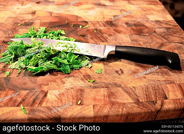 Closeup of a knife on a cutting board with fresh green mint