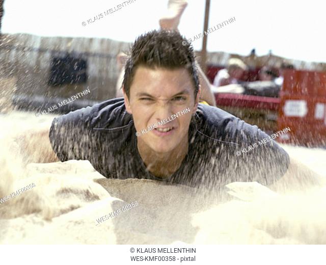Young man throwing sand, blurred motion
