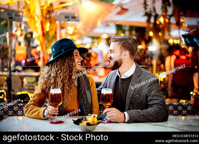 Couple drinking alcohol while sitting at beer garden in city