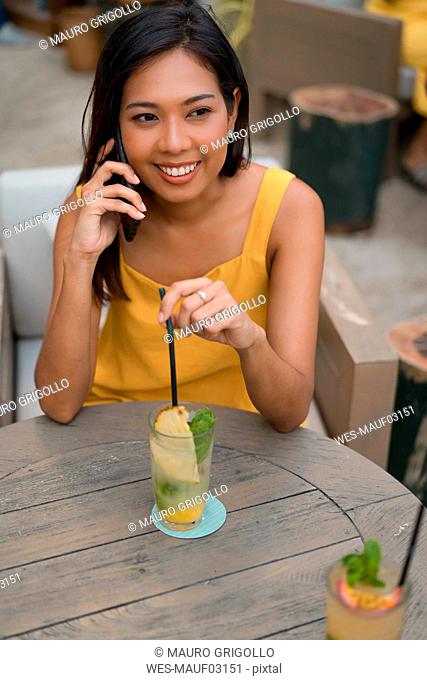 Portrait of smiling woman on the phone sitting in a cafe with a drink