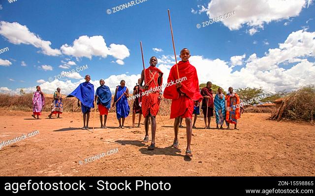 Unknown Masai village near Amboselli park, Kenya - April 02, 2015: Masai warriors lining up for traditional dancing and singing with deep blue sky in background