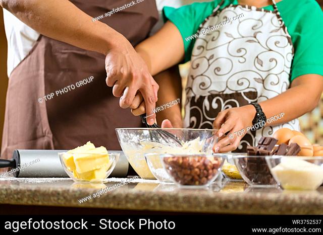 Asian couple, man and women, baking homemade cake in his kitchen for dessert
