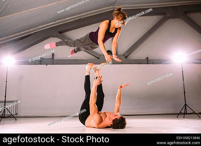 young couple Couple practicing acro yoga in gym. Healthy lifestyle. Acroyoga. Couple yoga. Partner yoga. Muscular man throwing women to air