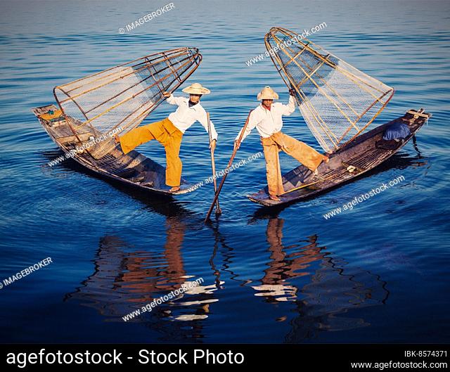 Myanmar travel attraction, Traditional Burmese fishermen balancing with fishing nets at Inle lake in Myanmar. Vintage filtered retro effect hipster style image