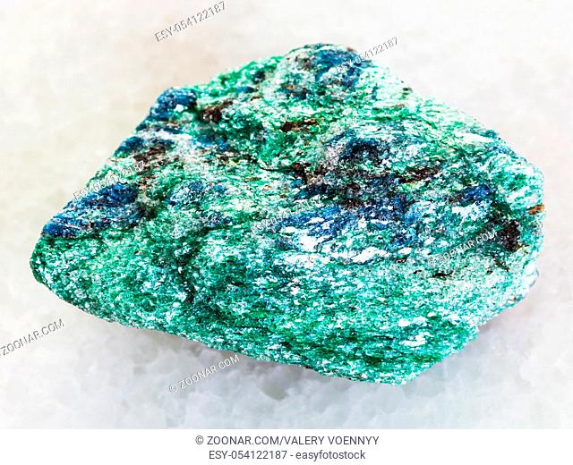 macro shooting of natural mineral rock specimen - raw Fuchsite (chrome mica) stone on white marble background from Hizovaara, Republic of Karelia in Russia