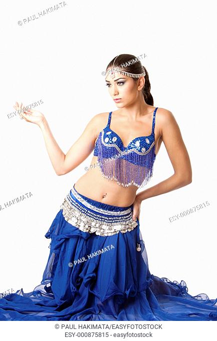 Beautiful Israeli Egyptian Lebanese Middle Eastern fashion belly dancer performer in blue skirt and bra sitting on knees, isolated