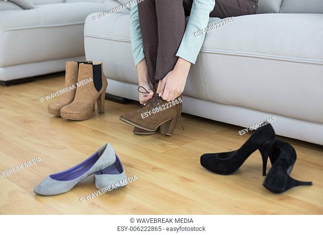 Slim woman tying her shoelaces sitting on couch