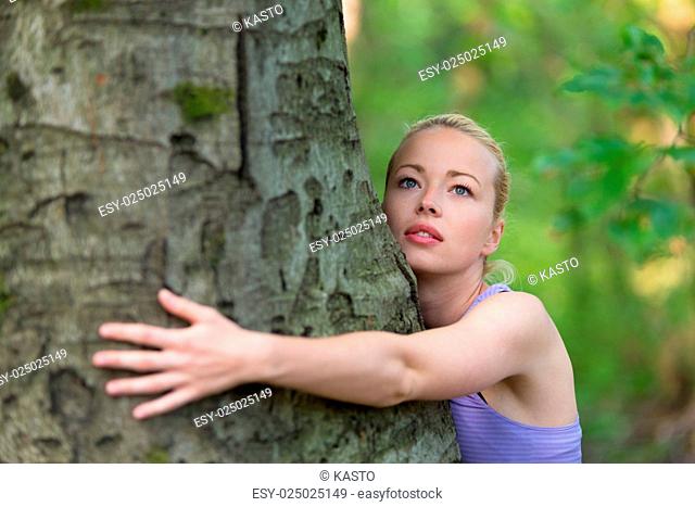 Relaxed young lady embracing a tree receiving life energy from the nature