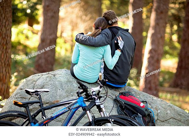 Biker couple sitting on rock in forest