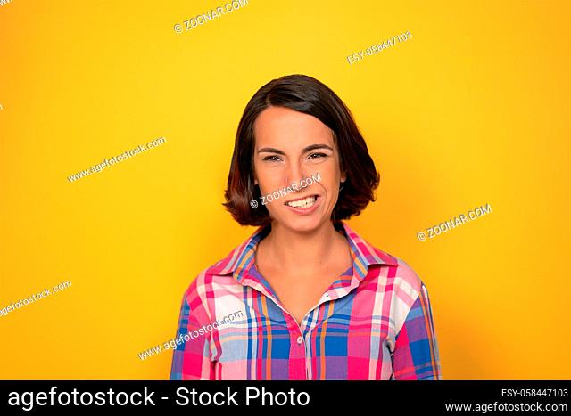 Emotional denial or hesitation charming brunette looking to camera. Young woman in a plaid shirt on yellow background. Human emotions, facial expression concept